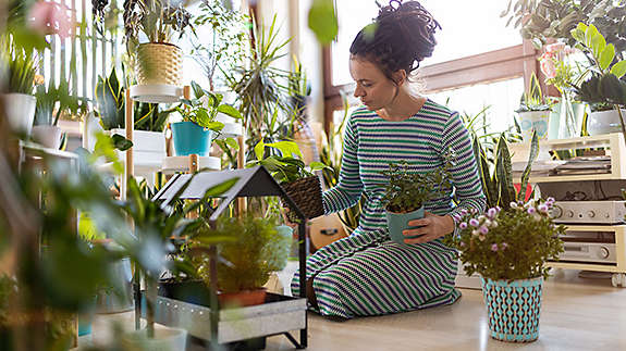 Woman sitting on her floor surrounded by plants 