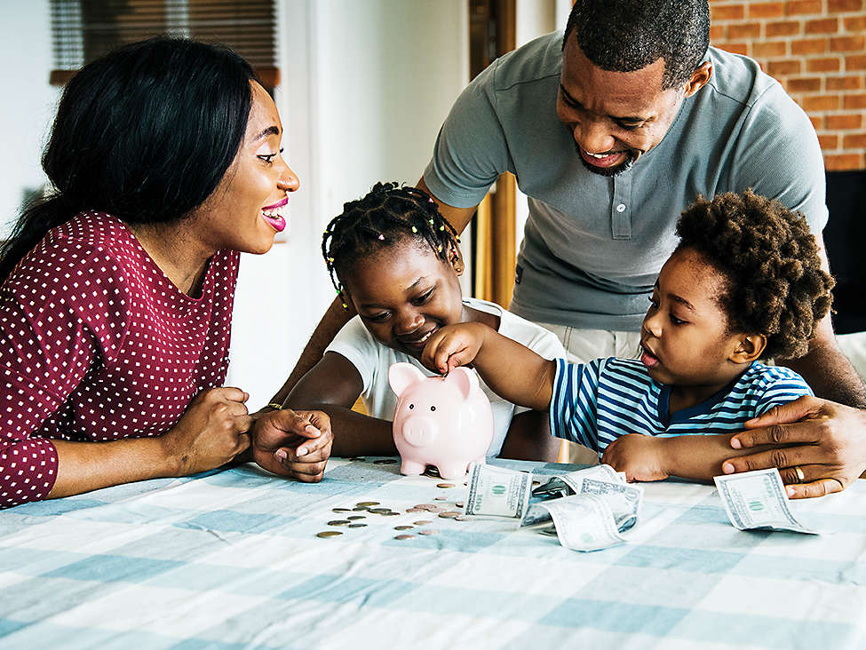 A family sitting at the table putting coins into piggy bank 