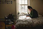 Young woman goes through paperwork on bed