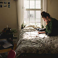 Young woman goes through paperwork on bed