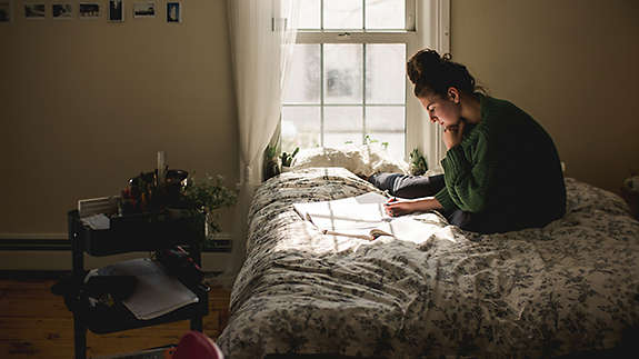 Young woman goes through paperwork on bed