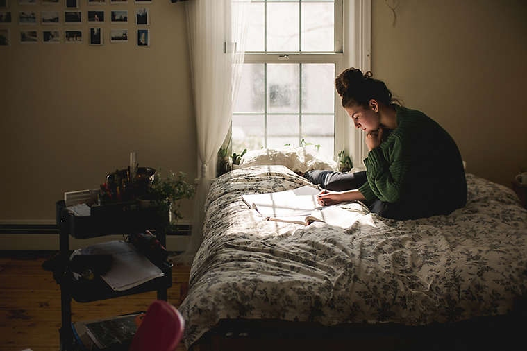 Young woman goes through paperwork on bed