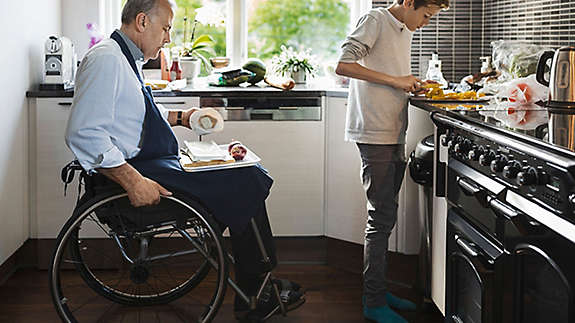 Middle-aged gentleman and son cooking together in kitchen