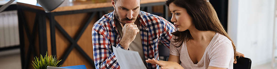 Couple sitting in their kitchen looking at paperwork.