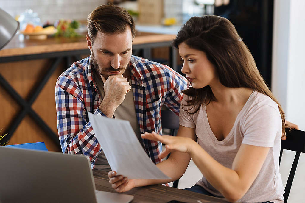 Couple sitting in their kitchen looking at paperwork.