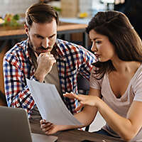 Couple sitting in their kitchen looking at paperwork.