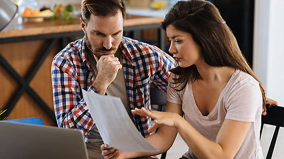 Couple sitting in their kitchen looking at paperwork.