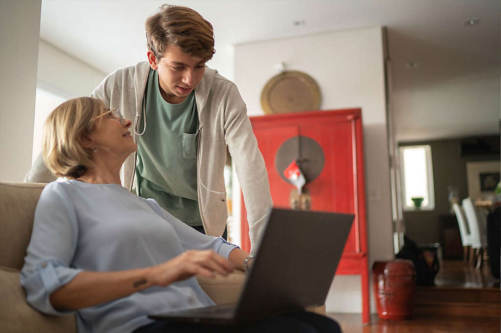 A woman talking to her grandson while working on a computer.