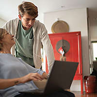 A woman talking to her grandson while working on a computer.