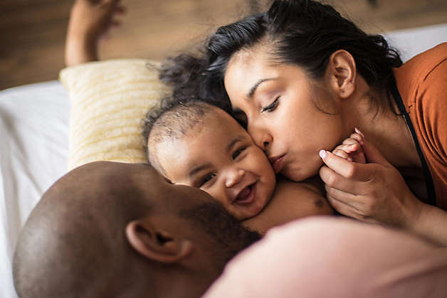 Young couple kissing their infant child