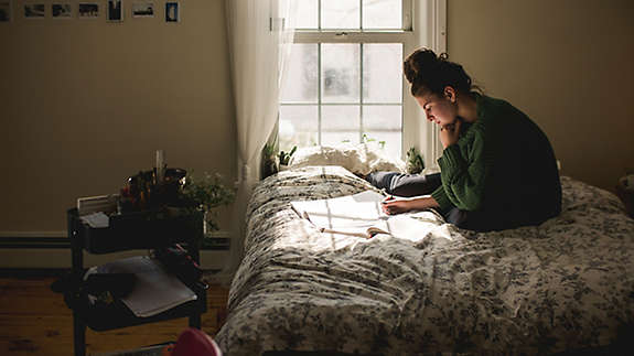 Young Woman Studying On Her Bed