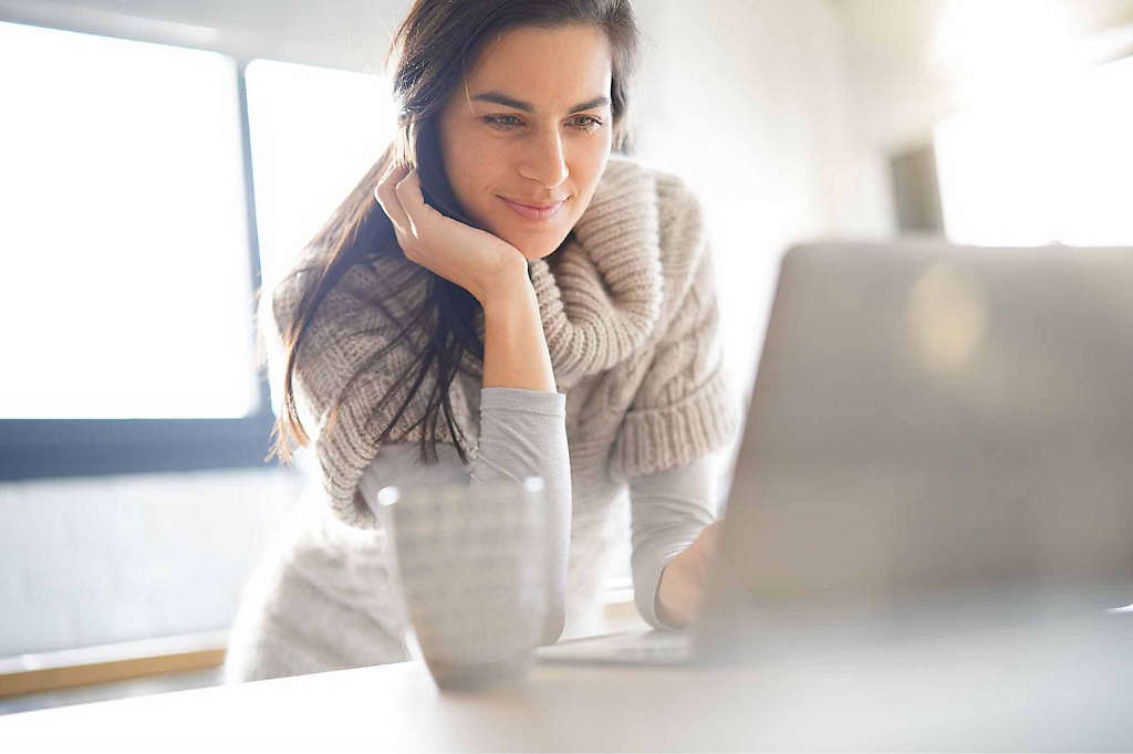 A woman setting up her first online trades on a laptop.