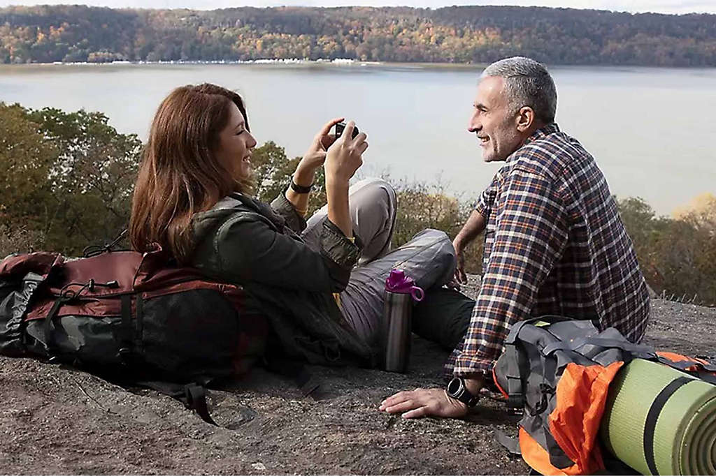 A retired couple enjoying the view of a lake after a hike. 