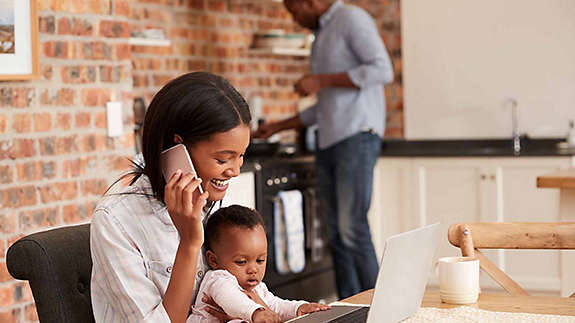 A woman sits with her young child at a computer as she starts a 529 college savings plan with help over the phone from an agent.
