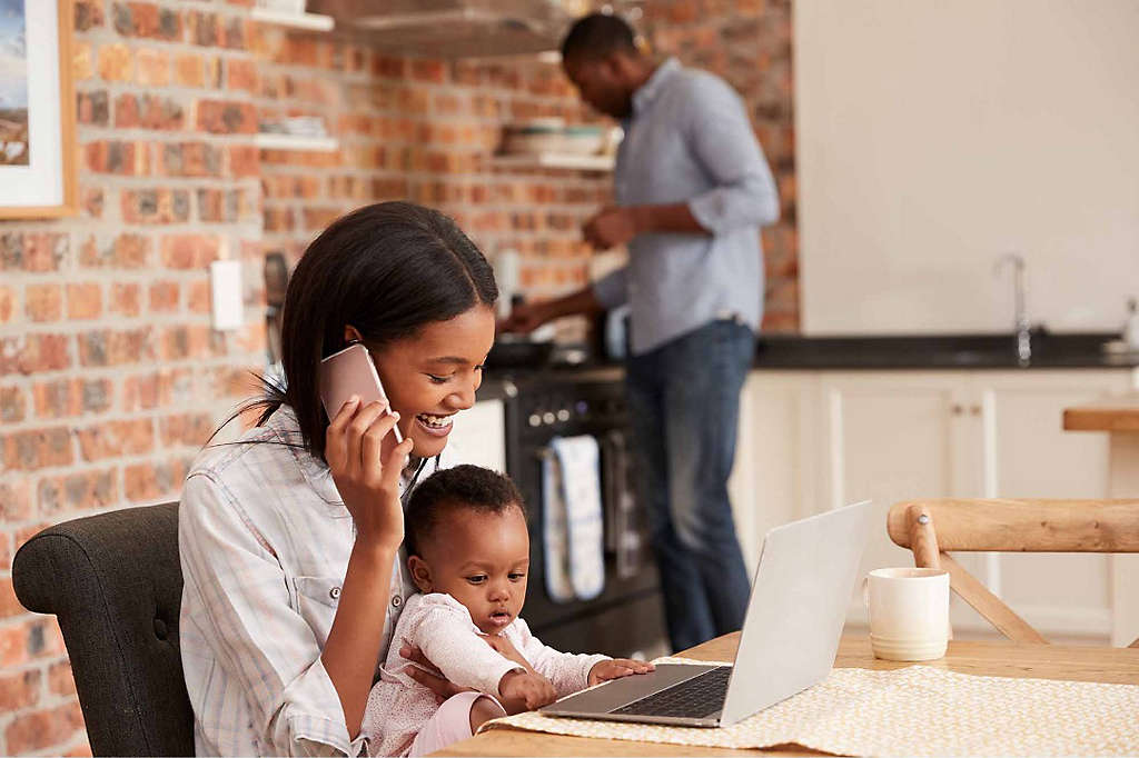 A woman sits with her young child at a computer as she starts a 529 college savings plan with help over the phone from an agent.