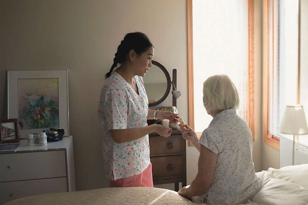 A home care provider helping an elderly woman with her prescriptions.