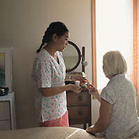 A home care provider helping an elderly woman with her prescriptions.