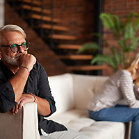 older couple sitting on opposite ends of sofa