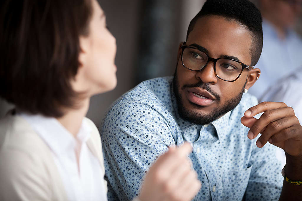 Multiracial colleagues talk discussing projects in office