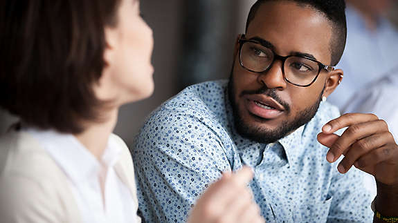 Multiracial colleagues talk discussing projects in office