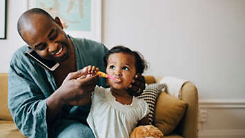 Dad brushing daughters teeth