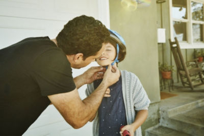 Dad teaching son to ride scooter