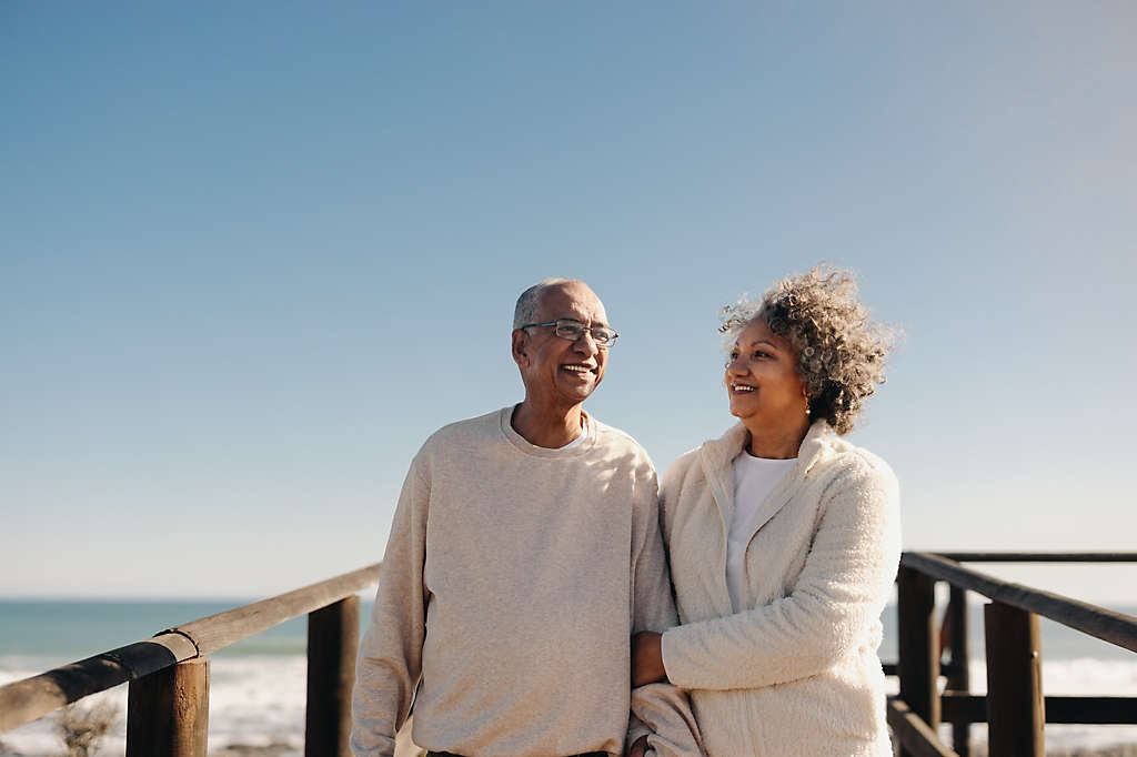 A couple standing on a boardwalk by the beach