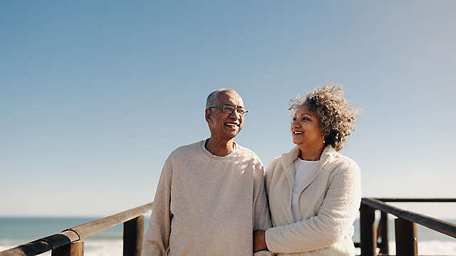 A couple standing on a boardwalk by the beach