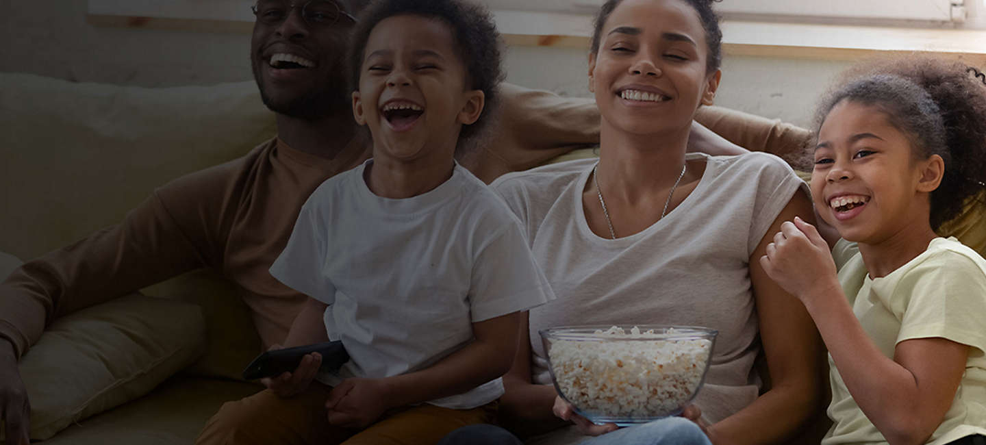 Family watches movie on couch with popcorn.