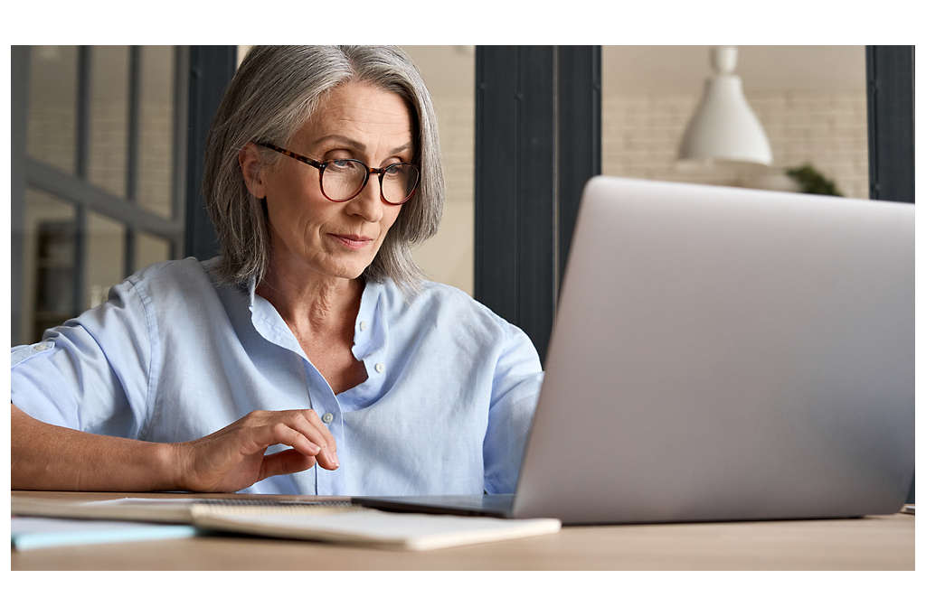 middle aged woman wearing glasses working on laptop