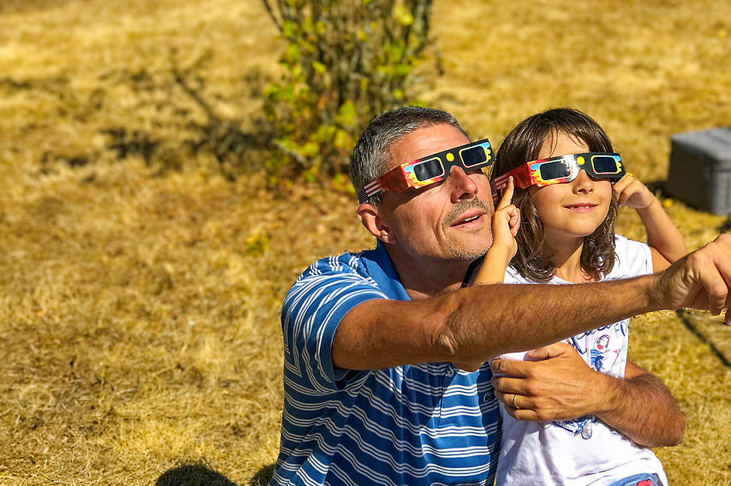 A father and daughter watching an eclipse