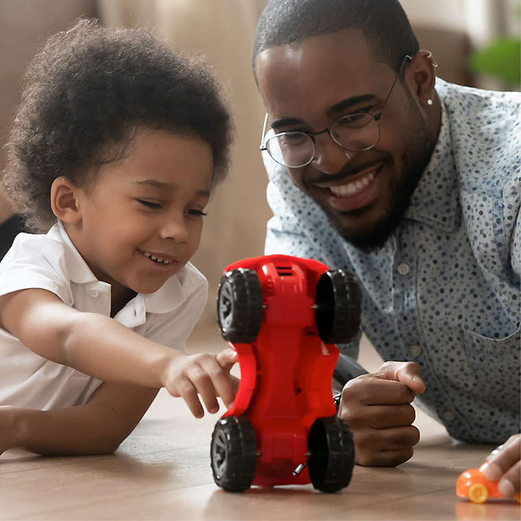 Father and son play with red race car toy
