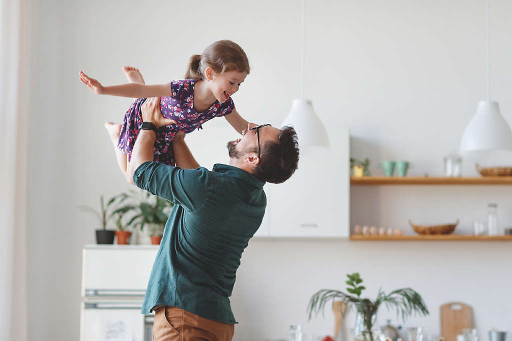 A father holding his young daughter in the air