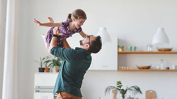 A father holding his young daughter in the air.