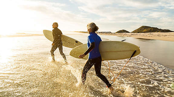 Two people with surfboards running into an ocean