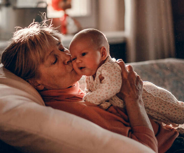 Grandmother holding grand baby on couch