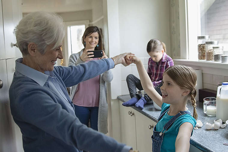 Grandmother and granddaughter dancing in kitchen