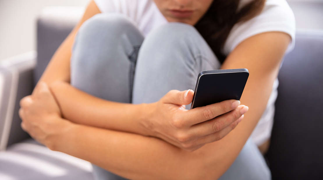Sad young woman holding a cell phone