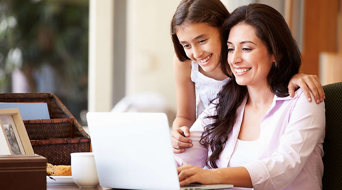  A parent and child looking at a laptop and smiling