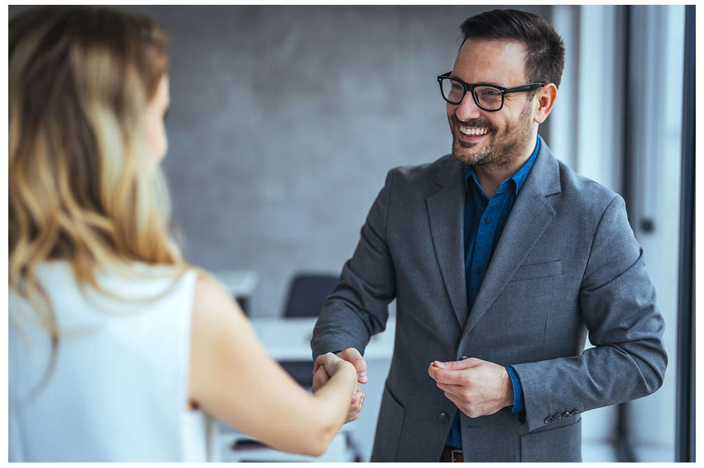 A man shaking hands with a woman colleague 