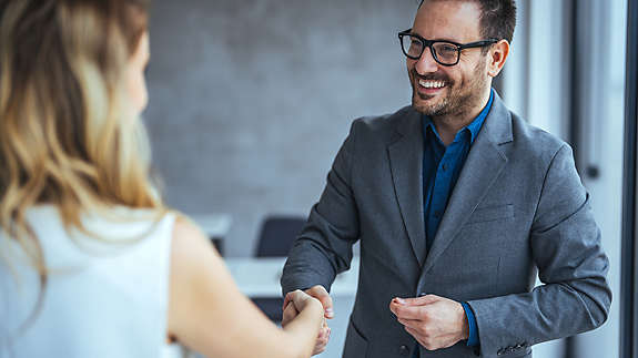 A man shaking hands with a woman colleague