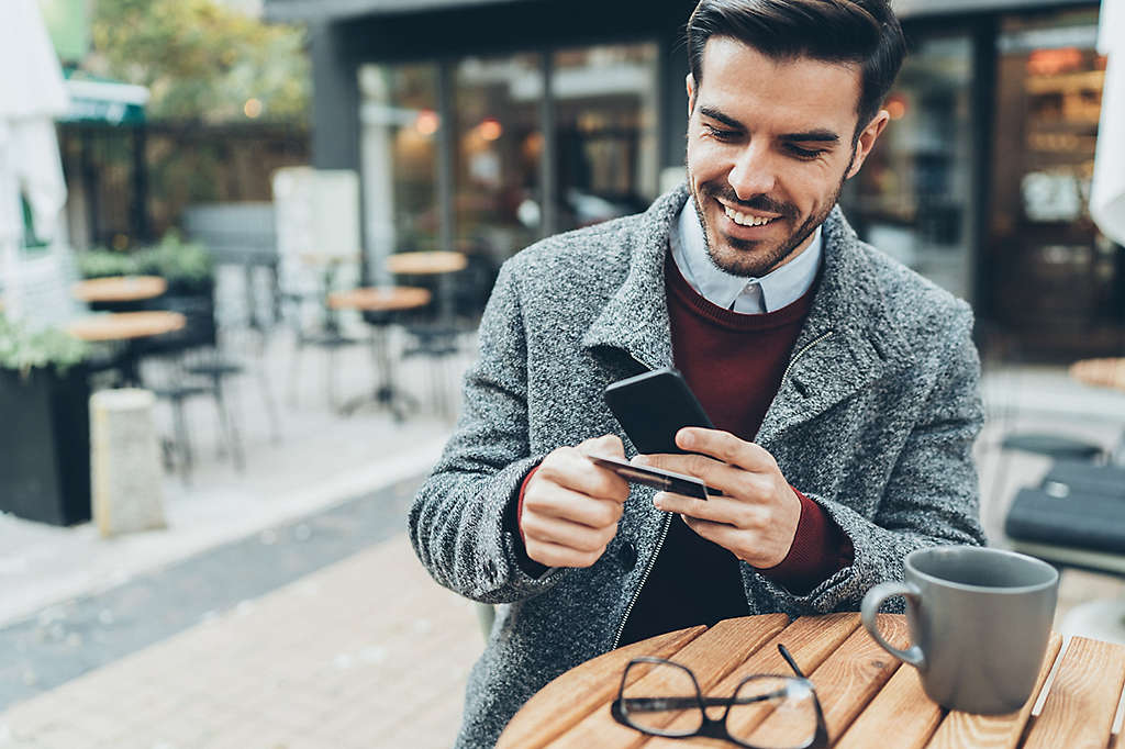 A man using his credit card while on his cell phone.