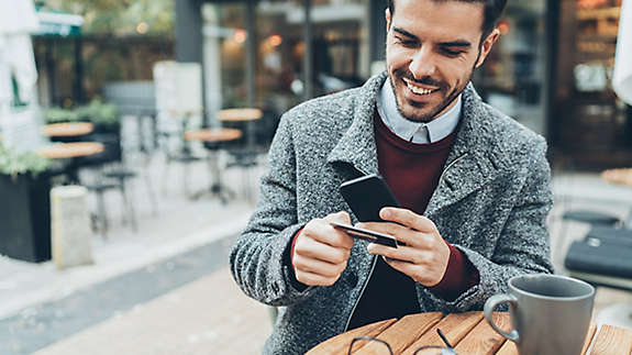 A man using his credit card while on his cell phone.