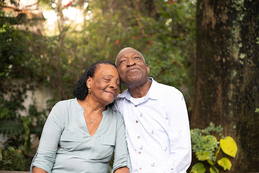 Older couple sitting outdoors among trees.