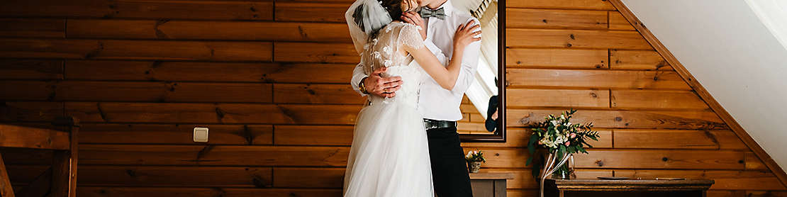 Bride and groom hugging and kissing indoors.
