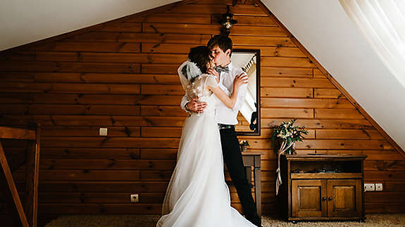 Bride and groom hugging and kissing indoors.