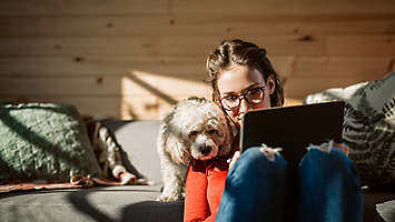 Young woman and her pet dog looking at a tablet.
