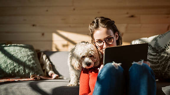 Young woman and her pet dog looking at a tablet.