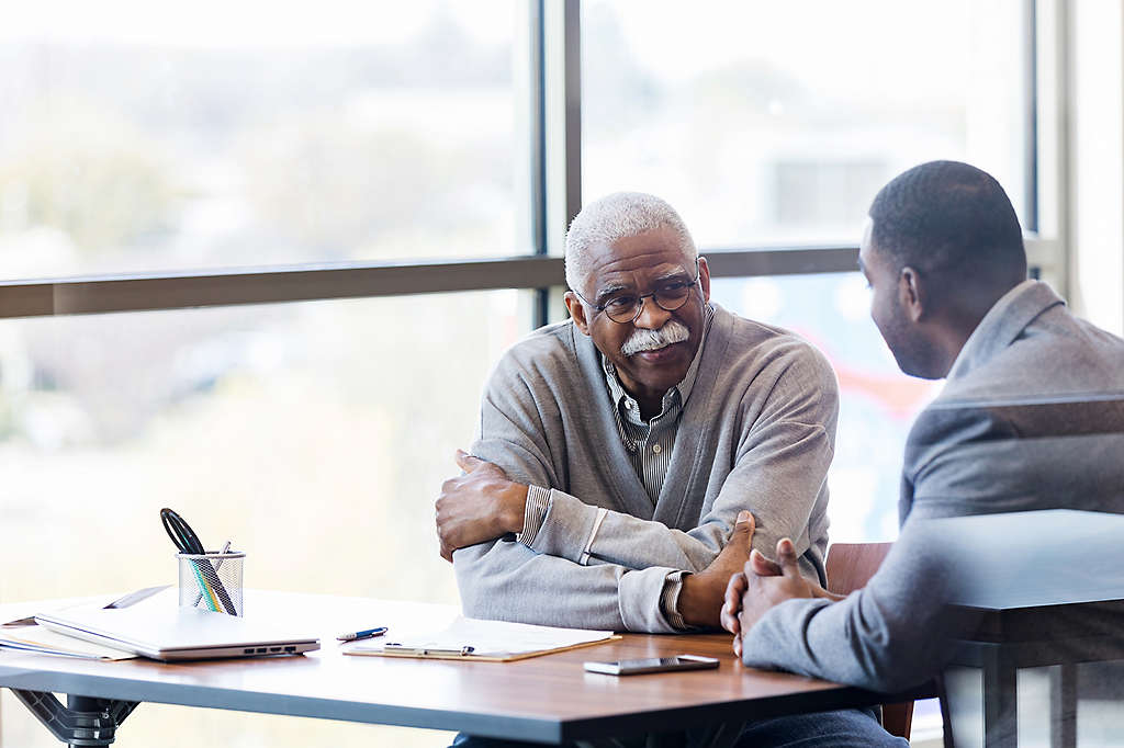 An older man talking at a table with his son.