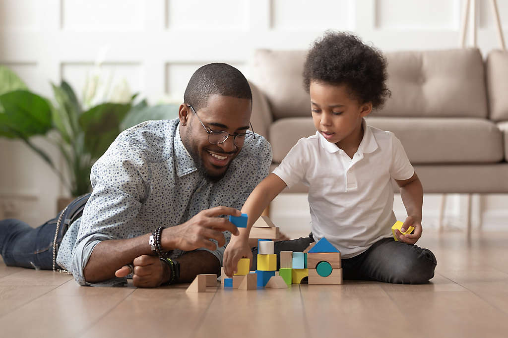 Father on the floor playing blocks with his son.